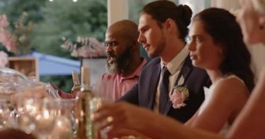 Çeşitli düğün davetlileri konuşuyor, içki dolduruyor, kadeh kaldırıyor ve resepsiyon masasında salata yiyor. Kutlama, dostluk, zarafet, neşe, açık hava, sofistike, sosyalleşme.