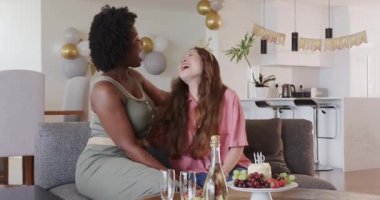 Afrikalı Amerikalı arkadaş ve Asyalı arkadaş evde doğum gününü pasta ve şampanyayla kutluyorlar. Kutlama, arkadaşlar, doğum günü, kapalı alan, modern, neşeli, şık