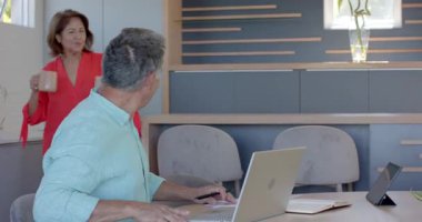 Birçok üst düzey çift kutlama için masa başında laptoplarını inceliyor. İşbirliği, akıl hocalığı, takım çalışması, kıdemli, modern, yerli, profesyonel