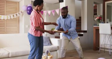 Evde kutlama yapıyoruz, neşeli bir çift atıştırmalıkların tadını çıkarıyor ve parti için dekorasyon yapıyor. Kutlama, şenlik, dekorasyon, mutluluk, birliktelik, etkinlik