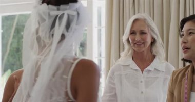 Soyunma odasına girmek, çeşitli kadın gelinlik partilerinin düğün duvağını mükemmel bir uyum için ayarlaması. Gelin, zarafet, işçilik, takım çalışması, kutlama, gelenek, kadınlık