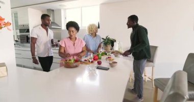 Çeşitli arkadaşlar gülüyor ve modern mutfakta birlikte sağlıklı yemekler hazırlıyorlar. Aşçılık, arkadaşlık, takım çalışması, yaşam tarzı, beslenme, aşçılık