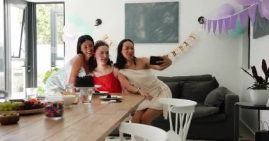 Çeşitli bayan arkadaşların telefonlarını dinlemesi, yemek odasında doğum günü pastasının fotoğrafını çekmesi, resimlerini incelemesi. Kutlama, dostluk, arkadaşlık, neşeli, canlı, sıradan, sosyalleşme.