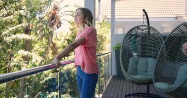 Balkonda genç bir çift, yüzüklü bir adam, şaşkınlıkla gülümseyen bir kadın. Teklif, nişan, romantizm, ilişki, aşk, bağlılık