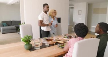 Çeşitli arkadaşlar akşam yemeğinin tadını çıkarıyor, evde içkilerle kadeh kaldırıyorlar. Kutlama, yemek, arkadaşlık, yaşam tarzı, kaynaşma, toplanma