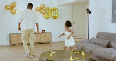 Doğum günü partisinde beyaz eşya taşıyan Afrikalı bir ebeveyn ve genç bir kız izliyor. Kutlama, sevinç, aile, toplanma, dekor, parti, bağ, mutluluk