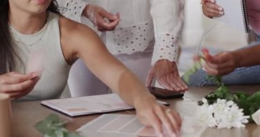 Üst düzey kadın çalışanlara ev masasında kumaş ve sapları ayırarak etkinlik planlamaları için rehberlik ediyor. İşbirliği, takım çalışması, yaratıcılık, çeşitlilik, akıl hocalığı, planlama, ilham