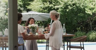 Çeşitli kadın arkadaşlar selamlaşır, hamur işleri sunar, su döker, verandadan pasta toplar. Açık hava, sosyalleşme, zarafet, eğlence, kutlama, yeşillik, yaşam tarzı.