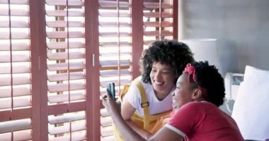 Afro-Amerikalı kadınlar evde tabletle gülüp eğleniyorlar. Arkadaşlar, teknoloji, yaşam tarzı, eğlence, mutluluk, bağlantı