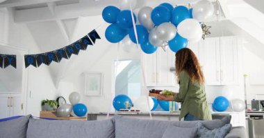 Olgun bir kadın doğum günü hazırlıyor, eve giriyor, üzümlü peynir yerleştiriyor ve şarap kadehi tutuyor. Kutlama, şenlik, konut, iç mekan, neşe, dekor, sosyalleşme