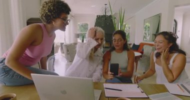 Çeşitli kadın iş arkadaşları akıllı telefonları dinliyor, yemek masasında ruh hali panosu inşa etmek için kumaş örnekleri hazırlıyorlar. İşbirliği, takım çalışması, yaratıcı, tasarım, modern, enerjik, iyimser