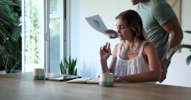 Genç bir çift evdeki belgeleri tartışıyor, ahşap masada birlikte oturuyorlar. tartışma, kağıt işleri, toplantı, yerli, kağıt işleri, yaşam tarzı