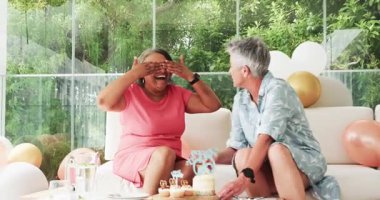 Modern ev ortamında 60. yaş gününü pastayla kutlayan kıdemli arkadaşlar. Kutlama, dostluk, neşe, coşku, toplanma, parti, şenlik