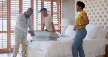 Aile bavullarını yatağın üzerine topluyor, tatillere hazırlanıyor, evde tebessümle ve heyecanla. seyahat, macera, turizm, neşe, hazırlık, yolculuk