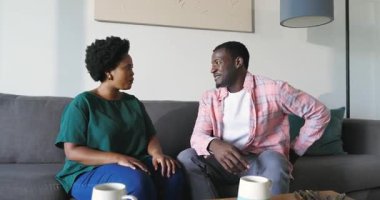 Adam, evinde mutlu bir şekilde gülümseyen bir kadına kanepede sürpriz yapmayı teklif ediyor. Teklif, nişan, aşk, mutluluk, romantizm, ilişki