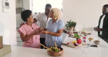 Modern mutfakta yemek hazırlamak, farklı arkadaşlar gülmek ve evde sohbet etmek. Aşçılık, sosyalleşme, arkadaşlık, kahkaha, aşçılık, ev