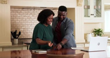 Afro-Amerikalı çift evde belgeleri inceliyor, dizüstü bilgisayarla gülümsüyorlar. Finans, takım çalışması, işbirliği, iş, yurt içi, mutluluk