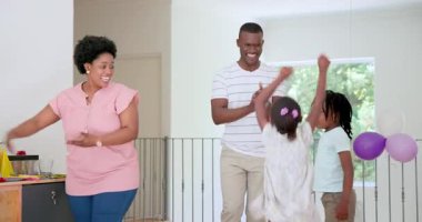 Afro-Amerikan ailesi doğum gününü evde parlak balonlar ve altın tacıyla kutluyor. Kutlama, doğum günü, neşeli, atmosfer, aile, şenlik, etkileşim, neşe