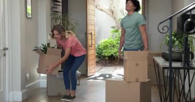 Etrafı kutularla çevrili genç çiftler yeni evlerine neşeyle giriyorlar. Yer değiştirme, paketleri açma, yeni başlangıçlar, ev sahipliği, heyecan, yaşam tarzı