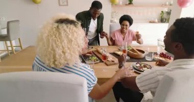 Çeşitli arkadaşlar brunch 'ın keyfini çıkarıyor, evde içkilerle kadeh kaldırıyor, gülümsüyor ve sohbet ediyorlar. Kutlama, yemek, konukseverlik, toplanma, içecek, kahkaha