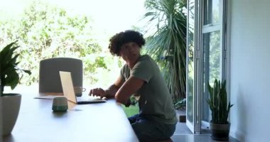 Evde dizüstü bilgisayarda çalışan genç bir çift. Etrafı yeşilliklerle çevrili. Takım çalışması, işbirliği, teknoloji, ev ofisi, uzaktan çalışma, yaşam tarzı