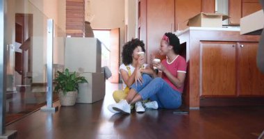 Çeşitli kadın çiftler yeni evlerinde kutuları açarken birlikte kahvenin tadını çıkarıyorlar. Taşınma, taşınma, yeni başlangıçlar, bağlanma, birliktelik, rahatlama.