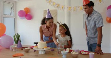 Çeşitli aileler doğum günü partisinde masanın etrafında toplanıp pasta ve canlı balonların tadını çıkarıyorlar. Kutlama, sevinç, ilişki, doğum günü, şenlik, birliktelik, atıştırmalıklar, coşku