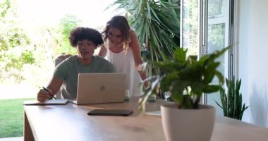 Evde genç bir çift birlikte dizüstü bilgisayar kullanıyor, işe ve işbirliğine odaklanıyor. Takım çalışması, teknoloji, uzaktan çalışma, ev ofisi, ortaklık