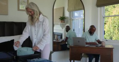 Masadan pasaport almak, bavulları boşaltıp yataktaki bavullara yerleştirmek. Seyahat, ambalaj, organizasyon, işbirliği, yaşam tarzı, yerli, evcimen