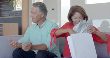 Çeşitli kardeşlerden paketler alan çift, bebek kıyafetlerini açıyor ve evde tezahürat yapıyor. Aile, kutlama, sürpriz, birlik, sevgi, sıcaklık, neşe