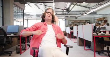 Masalar ve monitörler arasında, modern açık planlı ofiste ofis başkanıyla oynayan çeşitli iş arkadaşları. İş yeri, iç mekan, endüstriyel, parlak, ergonomik, işbirliği