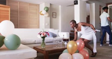 Partide, arkadaşlar doğum gününü evde kutlar, balon ve pasta düzenler, neşeli gülümsemeler sergilerler. Kutlama, dostluk, parti, dekorasyon, mutluluk, şenlik