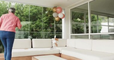 Üst düzey bayan arkadaşlar renkli balonlar ve dekoratif tellerle parlak bir ev dekore ediyorlar. Kutlama, dostluk, neşe, iç mekan, coşku, dekor, toplanma, kahkaha