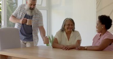 Kahve fincanları taşıyan ve hediye paketini açan bir adam yemek masasında son sınıf öğrencisi ve kızı için sürpriz bir hediye. Aile, bağ, kutlama, sıcaklık, şefkat, birliktelik, neşe