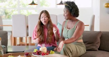 Afro-Amerikalı ve Asyalı arkadaşlar aydınlık oturma odasını temizliyor, pasta tabakları hazırlıyorlar. Temizlik, kutlama, dostluk, konfor, oturma odası, takım çalışması, çaba, temizlik, toplanma