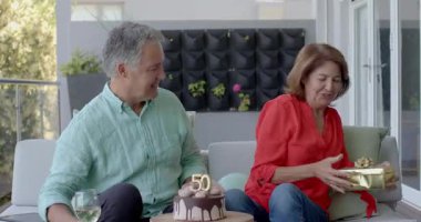 Son sınıf çifti teras kanepesinde şarap yudumluyor. Pastayı 50 sütle paylaşıyor. Altın bir hediye. Romantik, kutlama, açık hava, zarafet, arkadaşlık, neşe, eğlence