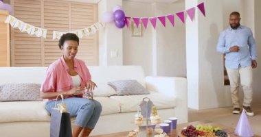 Doğum günü süslemeleri ve atıştırmalıkları hazırlayan Afro-Amerikan çift evde neşeli görünüyor. Kutlama, parti, dekorasyon, mutluluk, eğlence, şenlik