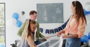 Doğum günü temizliğinden sonra oturma odasında elinde plastik çarşaf ve sırıkla gezen bir aile. Şenlik, kutlama, birliktelik, neşe, evcil, samimi, enerjik