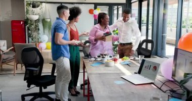 Modern ofiste çeşitli iş arkadaşları tebrik kartı, atıştırmalık ve balonlarla kutlama yapıyor. Kutlama, takım çalışması, başarı, iş yeri, şenlik, dostluk, başarılar