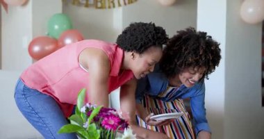 Kutlama sırasında evde gülümseyen ve kucaklaşan iki kadın. Arkadaşlık, mutluluk, neşe, birliktelik, kapalı mekanlar, aile