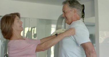 Gülümseyen son sınıf çifti, spor salonunda ilerleme kaydetmek için birbirlerinin gövdelerini mor bant ile ölçtükten sonra. Fitness, sağlık, arkadaşlık, kreatif, sağlıklı yaşam tarzı, aktif yaşlanma, vücut ölçümü.