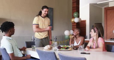 Partide, öğle yemeğini paylaşırken, arkadaşlar restoranda yemek masasında gülüp sohbet ederken. Arkadaşlık, sosyalleşme, kahkaha, sohbet, gastronomi, eğlence.