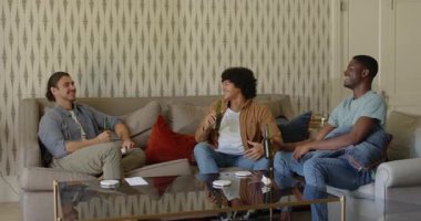 Çeşitli erkek arkadaşlar kanepede bira şişelerini tokuşturur, sarılır, tablet tıkırdatır. Kutlama, yoldaşlık, sosyal, boş zaman, rahatlama, mutluluk, arkadaşlık.