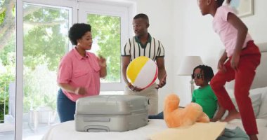 Afro-Amerikalı bir aile bavullarını toplayıp parlak bir evde oyuncak ayıyla oynuyorlar. Aile, toplanma, çocukluk, oyun zamanı, mutluluk, ışık, macera