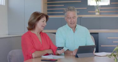 Çeşitli çiftler kredi kartlarını merkezdeki tablette gözden geçiriyorlar ve kilometre taşını sarılarak kutluyorlar. Aile, işbirliği, teknoloji, başarı, samimiyet, kutlama, rahatlık