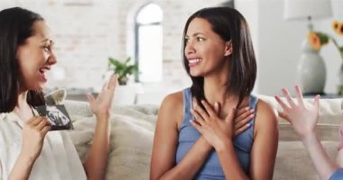 Çeşitli bayan arkadaşlar ultrason taraması, açılış kartı, koltukta sarılıp hamileliği kutluyorlar. Arkadaşlık, neşe, kutlama, çeşitlilik, modern iç mekan, bağlantı, mutluluk