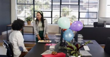 Mutlu iş adamı, ofisindeki balonlu iş kadınının mumlarıyla pasta yiyor. Ofis partisi, eğlence, kutlama, iş, ofis ve iş ortamı kavramı.