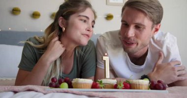 Evde, keklerle yatakta dinlenirken, çiftler birbirlerine üzüm yediriyorlar. Romantik, samimi, ilişki, birliktelik, bağlanma, boş zaman