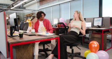 Çeşitli iş arkadaşları doğum gününü modern açık planlı ofiste pasta, balon ve hediye kutusuyla kutluyorlar. Şenlik, iş yeri, takım çalışması, açılma, endüstriyel, parlak, mumlar