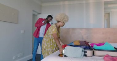 Çeşitli çiftler yatak odasında bavullarını topluyor, heyecan içinde evde seyahat planlarını tartışıyorlar. tatil, planlama, turizm, hazırlık